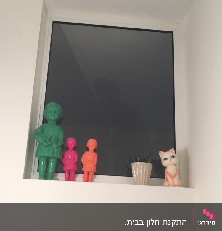 חלון אלומיניום עם פסלונים צבעוניים על אדן החלון